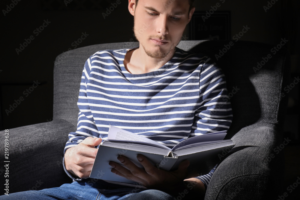 Young man reading book in evening at home Young man reading book in evening at home