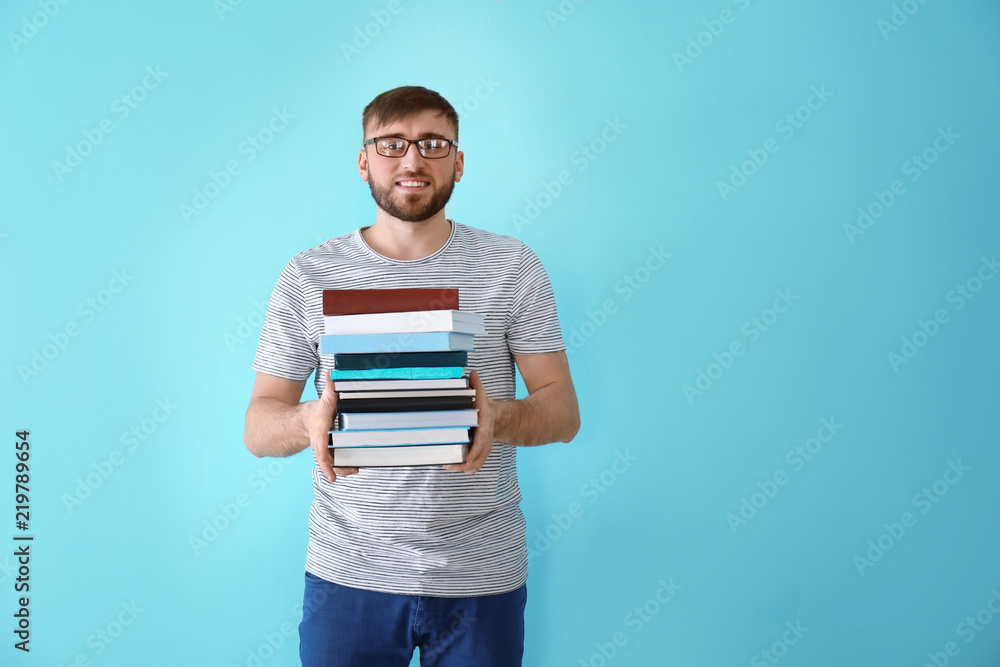 Young man with stack of books on color background Young man with stack of books on color background
