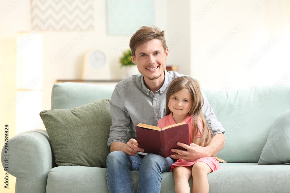 Father and his daughter reading book together at home Father and his daughter reading book together at home