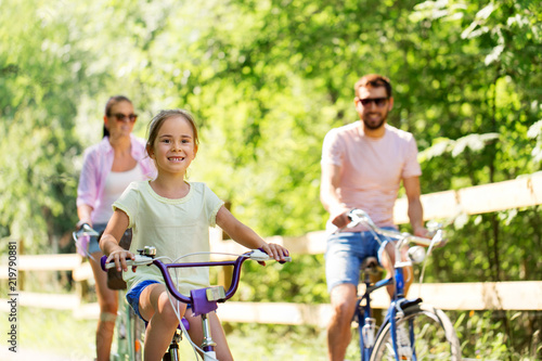 family, leisure and people concept - happy mother, father and little daughter riding bicycles in summer park © Syda Productions