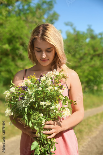 Young woman holding bouquet of beautiful flowers outdoors © Pixel-Shot