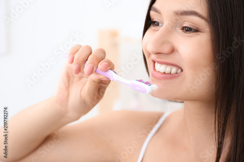 Young woman brushing her teeth in bathroom