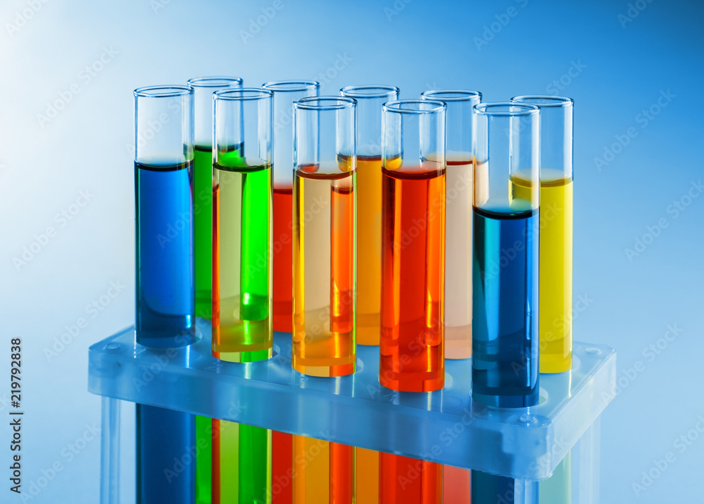 Test tubes with colorful liquids in holder on light background Test tubes with colorful liquids in holder on light background