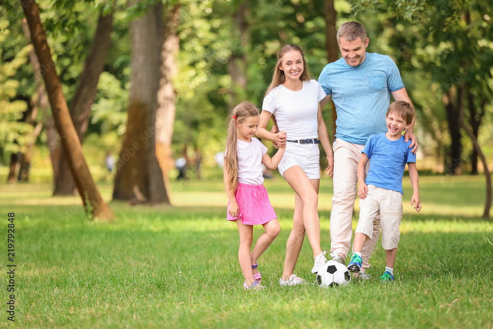 Happy family playing football in park on summer day Happy family playing football in park on summer day