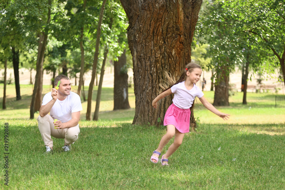 Happy father and daughter blowing soap bubbles in park Happy father and daughter blowing soap bubbles in park