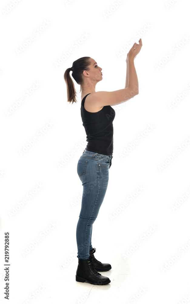 full length portrait of brunette girl wearing black single and jeans. standing pose in side profile. isolated on white studio background. full length portrait of brunette girl wearing black single and jeans. standing pose in side profile. isolated on white studio background.
