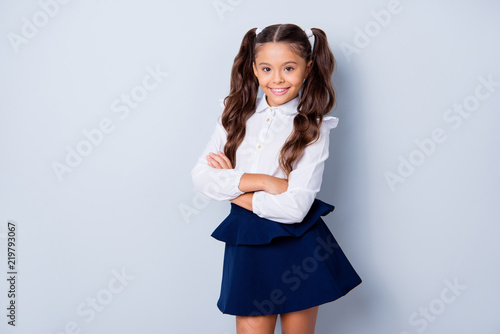 Obraz na plátně Back to school! Nice cute tender cheerful adorable lovely stylish girl with curly pony-tails in white formal blouse and dark blue skirt, folded arms
