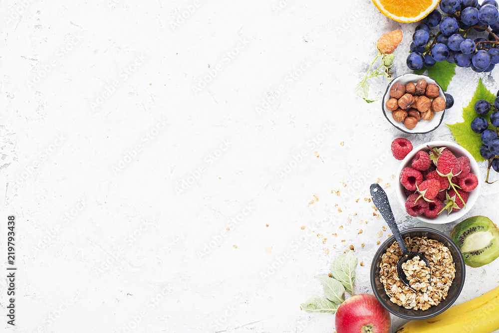 Plakat Składniki na zdrowe posiłki śniadaniowe: maliny, jagody, orzechy, pomarańcze, banany, winogrona niebieskie, zielone, jabłka, kiwi. Widok z góry.