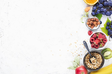 Ingredients for healthy breakfast meals: raspberries, blueberries, nuts, orange, bananas, grapes blue, green, apples, kiwi. Top View.