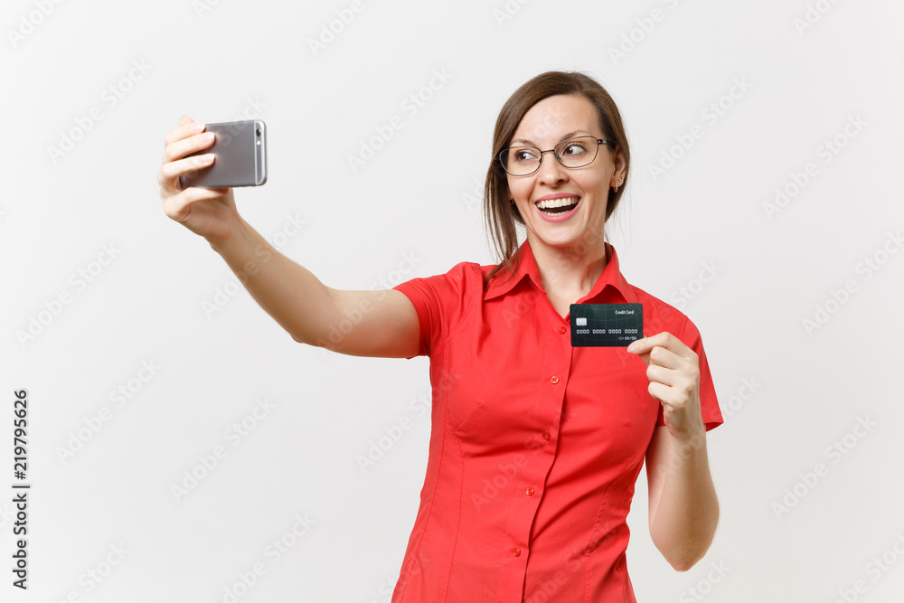 Excited business woman in red shirt doing taking selfie shot on mobile phone with credit bank card, cashless money isolated on white background. Education teaching in high school university concept. Excited business woman in red shirt doing taking selfie shot on mobile phone with credit bank card, cashless money isolated on white background. Education teaching in high school university concept.