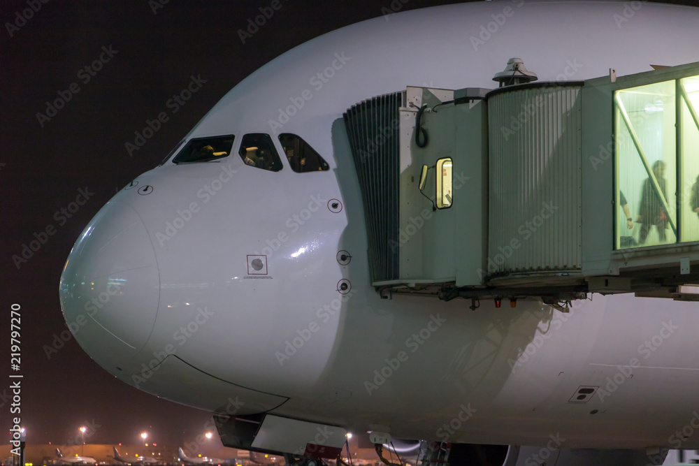 Passengers depart from the aircraft. The plane is standing by the tunnel at the night airport. Passengers depart from the aircraft. The plane is standing by the tunnel at the night airport.