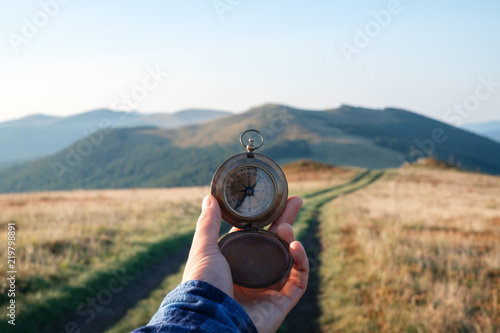 Man with compass in hand on mountains road. Travel concept. Landscape photography