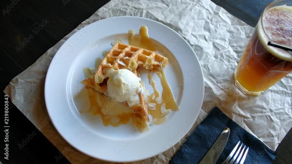 Top view - waitress delivers the dish dessert on the table in the restaurant. 4k. creamy ice cream with baked waffle. Top view - waitress delivers the dish dessert on the table in the restaurant. 4k. creamy ice cream with baked waffle.
