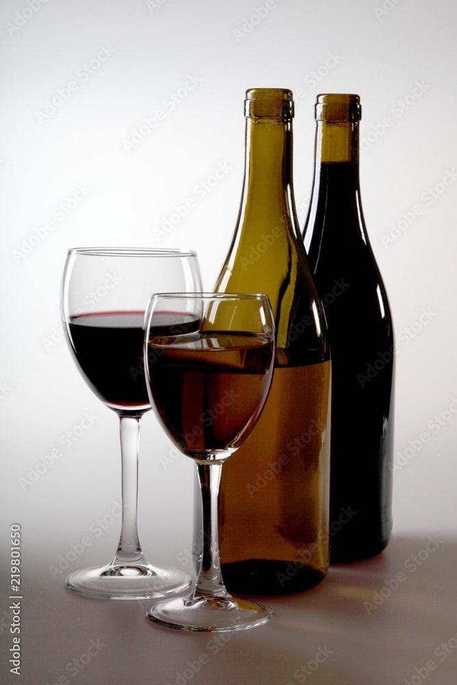 A glass of white wine and a glass of red wine next to bottles of A glass of white wine and a glass of red wine next to bottles of