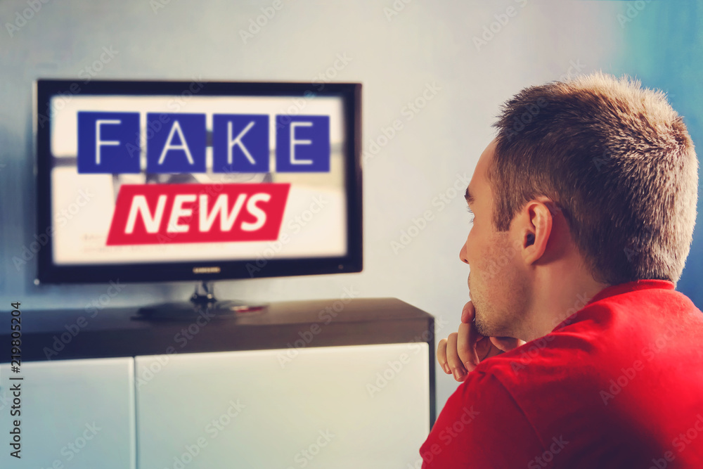 Foto Stock lies of tv propaganda mainstream media disinformation, A fake  news report. viewer is watching TV and doesn't believe in fake news. man  closes his eyes not to watch the lies