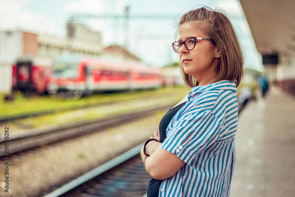 Front view of a sad young girl standin alone in a train statioin. woman looking away waitin Front view of a sad young girl standin alone in a train statioin. woman looking away waitin
