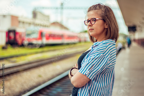 Front view of a sad young girl standin alone in a train statioin. woman looking away waitin photo