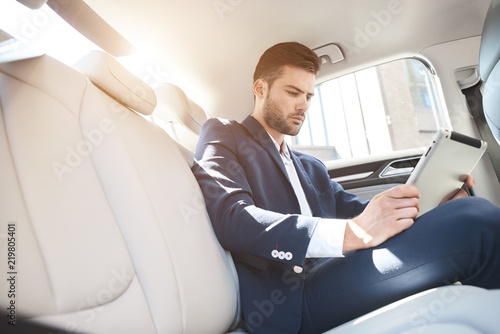 Portrait of а businessman using digital tablet while travelling in a car © Friends Stock