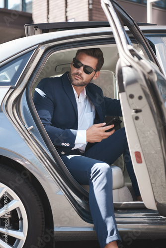 Фотография Confident businessman. Fashionable man coming out of a car