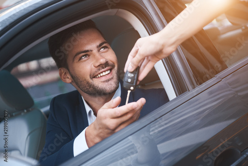 Car dealership.Young man receiving car key from saleswoman. photo