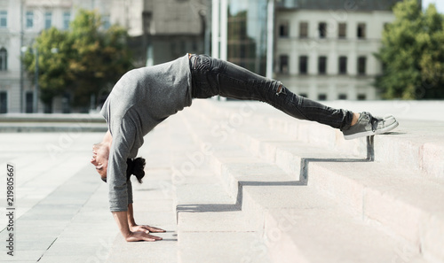 Man doing advanced yoga asana outdoors, side view © Prostock-studio