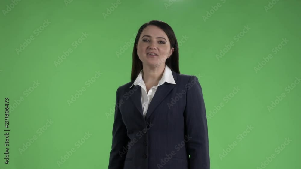 Cheerful woman in dark suit talking to camera against a green screen medium shot Cheerful woman in dark suit talking to camera against a green screen medium shot