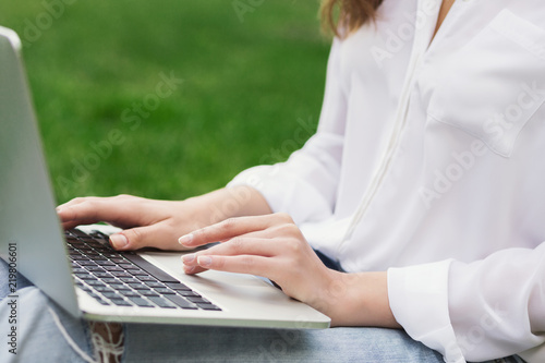 Woman hands typing on laptop keyboard outdoors