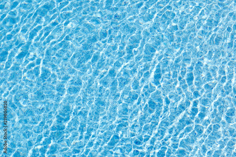 The movement of water in the blue pool with sun glare. Background image.