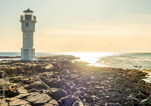The old inactive Akranes lighthouse at end of peninsula in city, was built since 1918, under blue sky, Iceland
