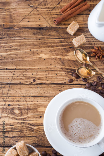 Cup of coffee, brown sugar and cinnamon with anise on a wooden background. Copy space