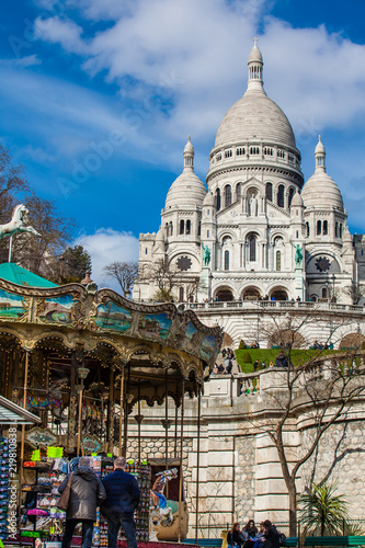 PARIS, FRANCE - MARCH, 2018: Carrousel and the Sacre Coeur Basilica at the Montmartre hill in Paris France
