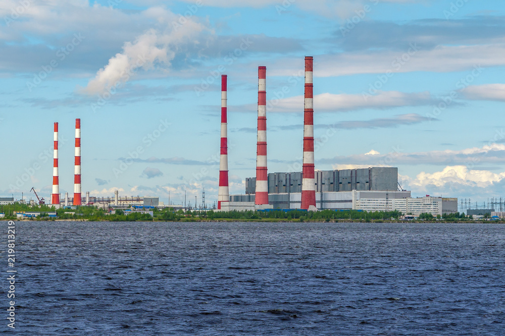Thermal power plants with bright chimneys on the shore of the reservoir in a bright sunny day. Thermal power plants with bright chimneys on the shore of the reservoir in a bright sunny day.