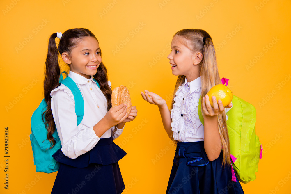 Profile side view photo of two small girls isolated on shine yellow background eat at home a meal telling each other incredible stories Profile side view photo of two small girls isolated on shine yellow background eat at home a meal telling each other incredible stories