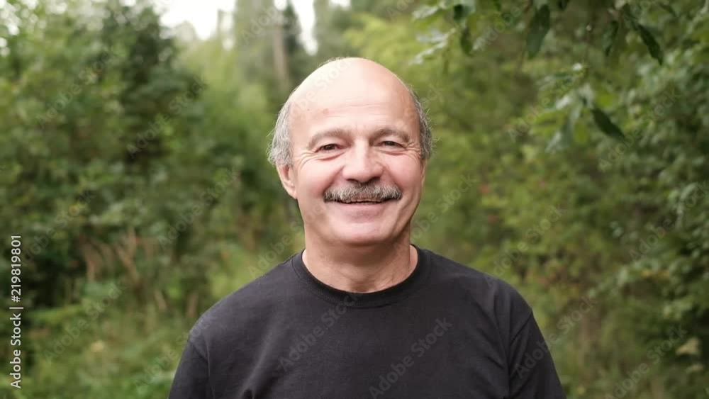 happy senior caucasian man walking outside in park by trees. He has positive thoughts and dreams happy senior caucasian man walking outside in park by trees. He has positive thoughts and dreams