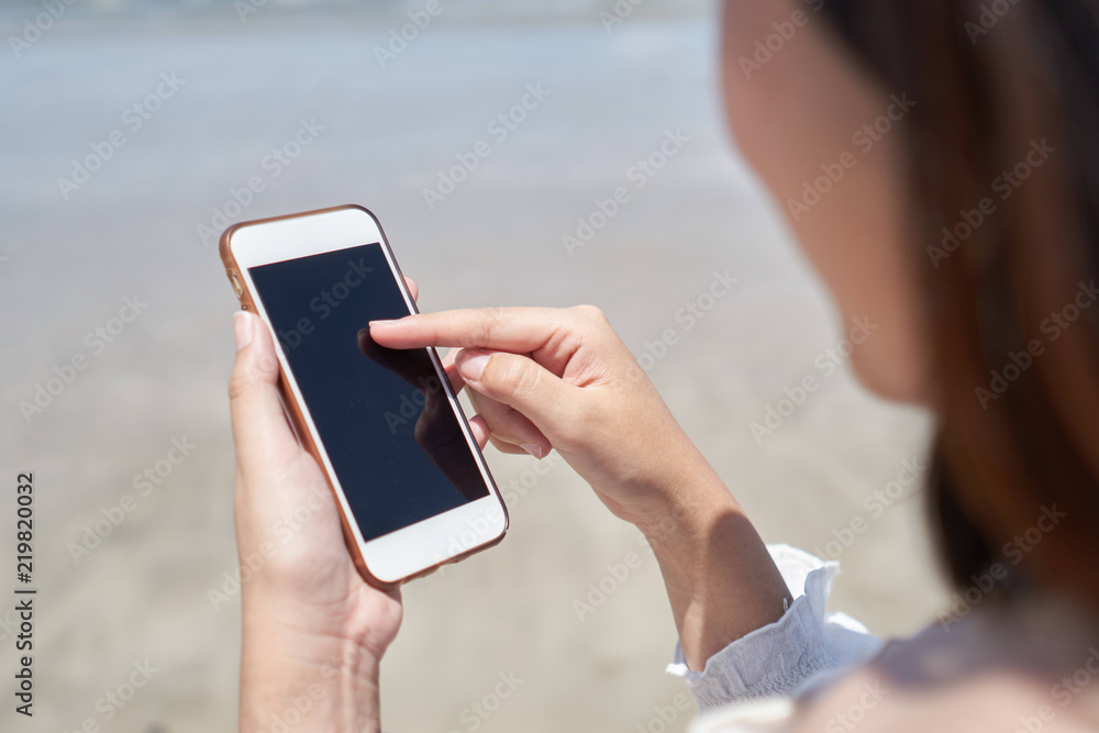 Woman using smart phone the beach on relax time.