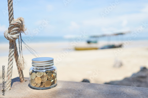 Gold coin in bottle on swing with sea and beach background, Growth for the save money concept
