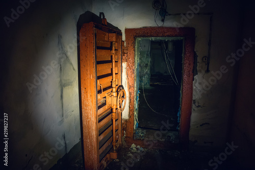 Large steel hermetic door of airlock in abandoned Soviet bunker in flashlight light photo