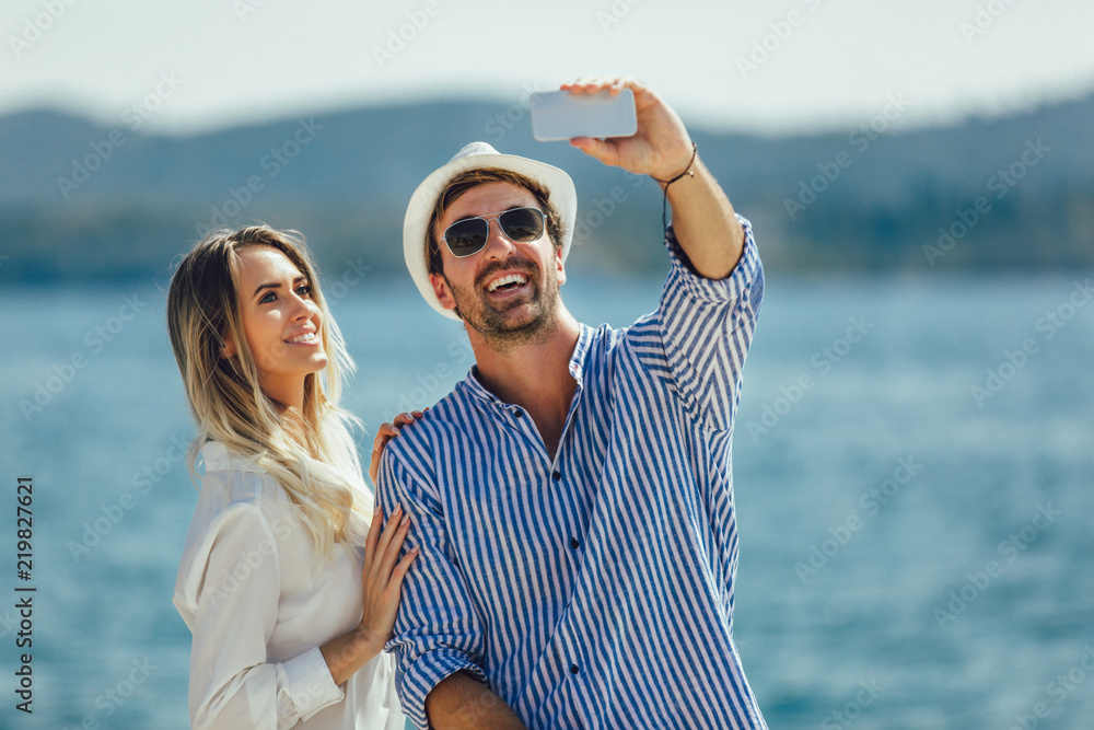 Couple in love, enjoying the summer time by the sea make selfie photo with smart phone