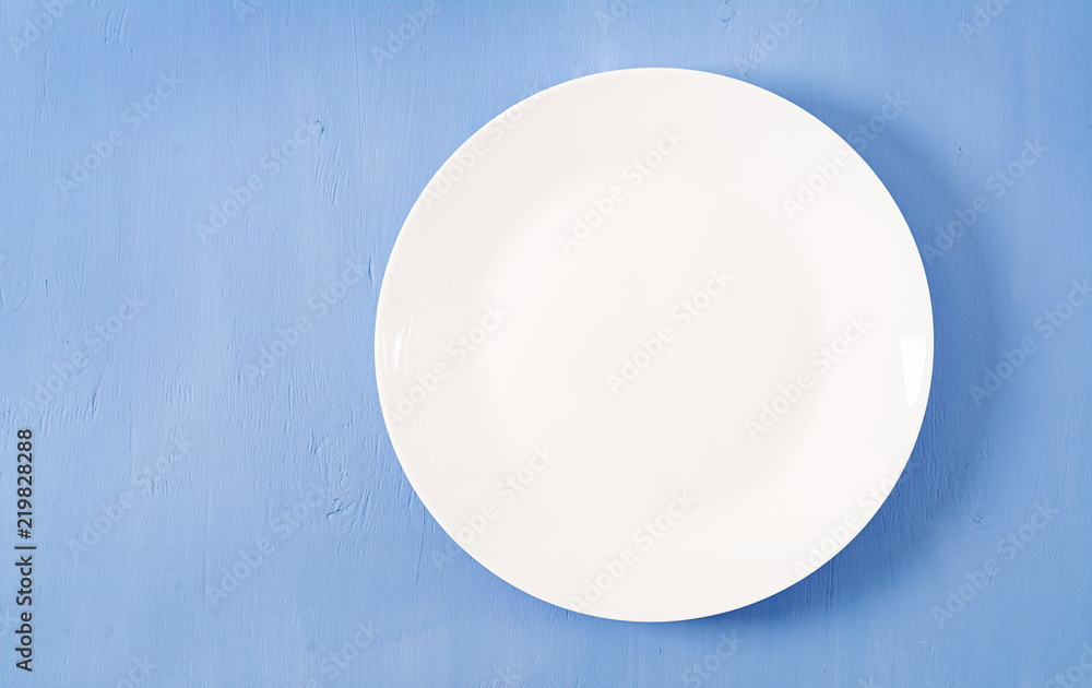 Top view of blank white dish on a blue background. Copy space. Mockup Top view of blank white dish on a blue background. Copy space. Mockup