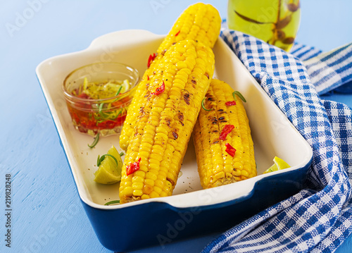 Fototapeta Naklejka Na Ścianę i Meble -  Grilled sweet corn with mexican sauce, chilli and lime on blue background. Healthy summer food.