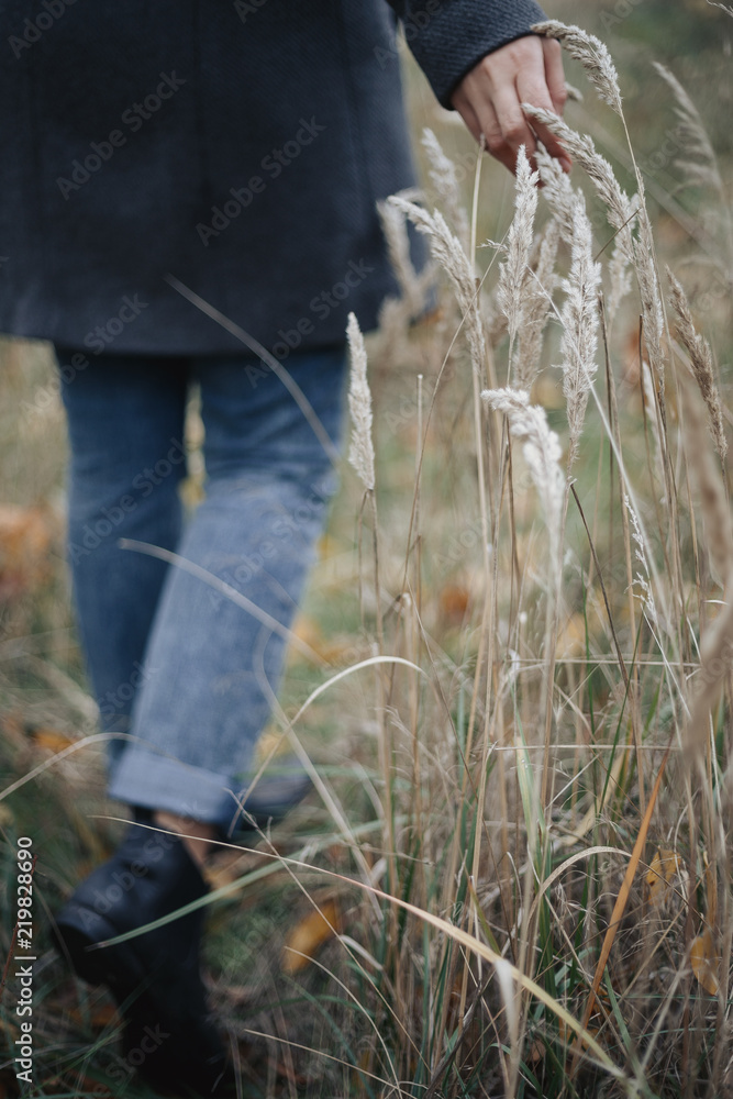 Woman in grey overcoat walking on the field and touching spikelets. Woman in grey overcoat walking on the field and touching spikelets.