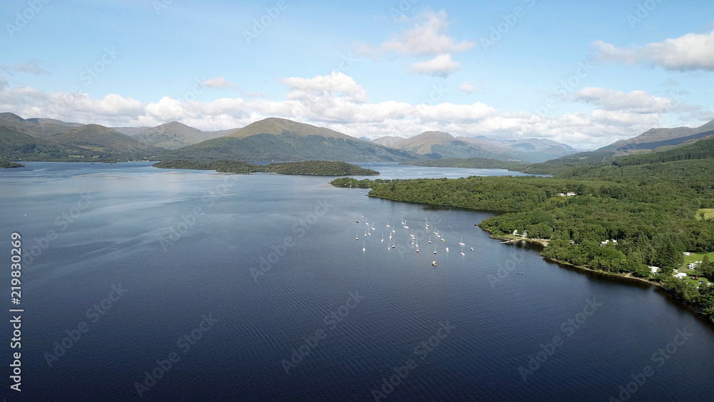 Aerial image of boats on a lake with islands and hills in the distance on a bright summer’s day. Aerial image of boats on a lake with islands and hills in the distance on a bright summer’s day.
