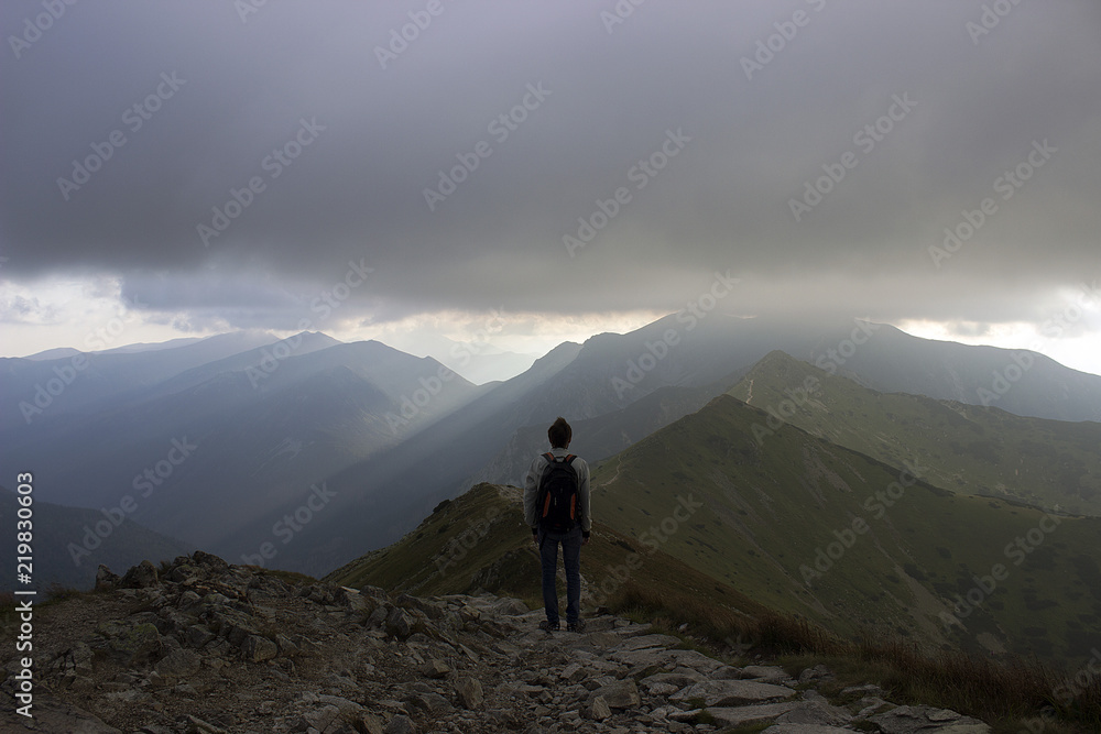 A male mountaineer looking over a vast, rocky, mountainous sunrise scene.
