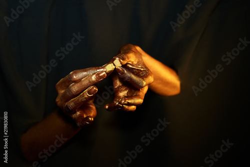 two golden hands holding a tooth and a crown on a black background © Mihail