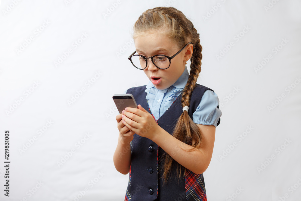 The little girl looks at her mobile phone in surprise