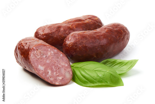 Bratwurst smoked pork sausages with sausage slices and green fresh basil leaves, isolated on white background.
