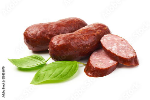 Bratwurst smoked pork sausages with sausage slices and green fresh basil leaves, isolated on white background.