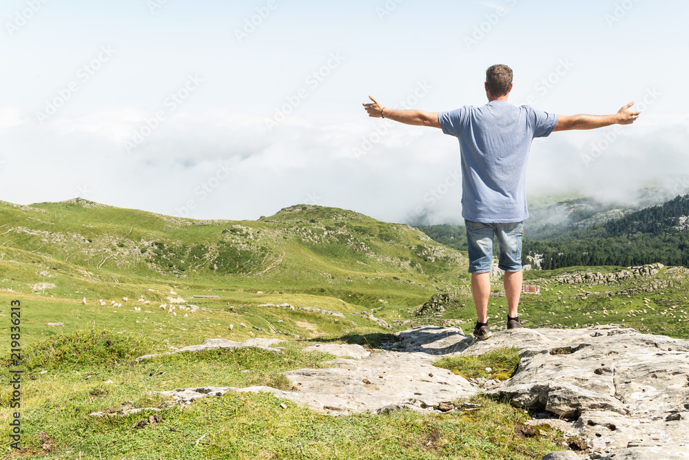 Hombre joven con los brazos abiertos en la cima de una colina mirando el horizonte. Momento inspirador. Hombre joven con los brazos abiertos en la cima de una colina mirando el horizonte. Momento inspirador.