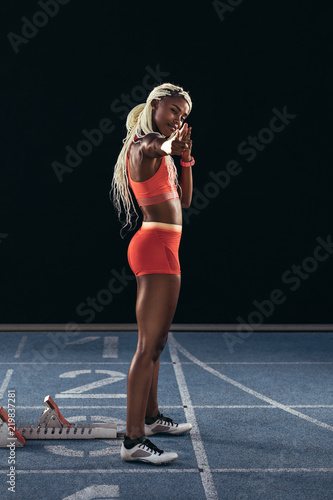 Female athlete in a cheerful mood standing on a running track