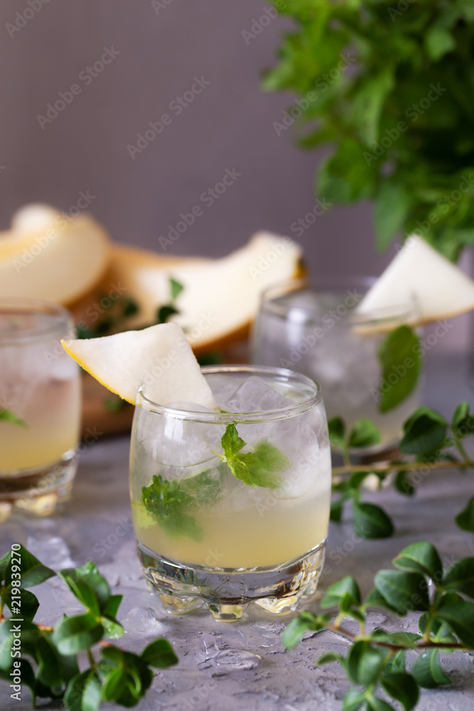 Melon lemonade decorated fresh mint in a glasses on the gray table. Summer refreshing drink. Melon lemonade decorated fresh mint in a glasses on the gray table. Summer refreshing drink.